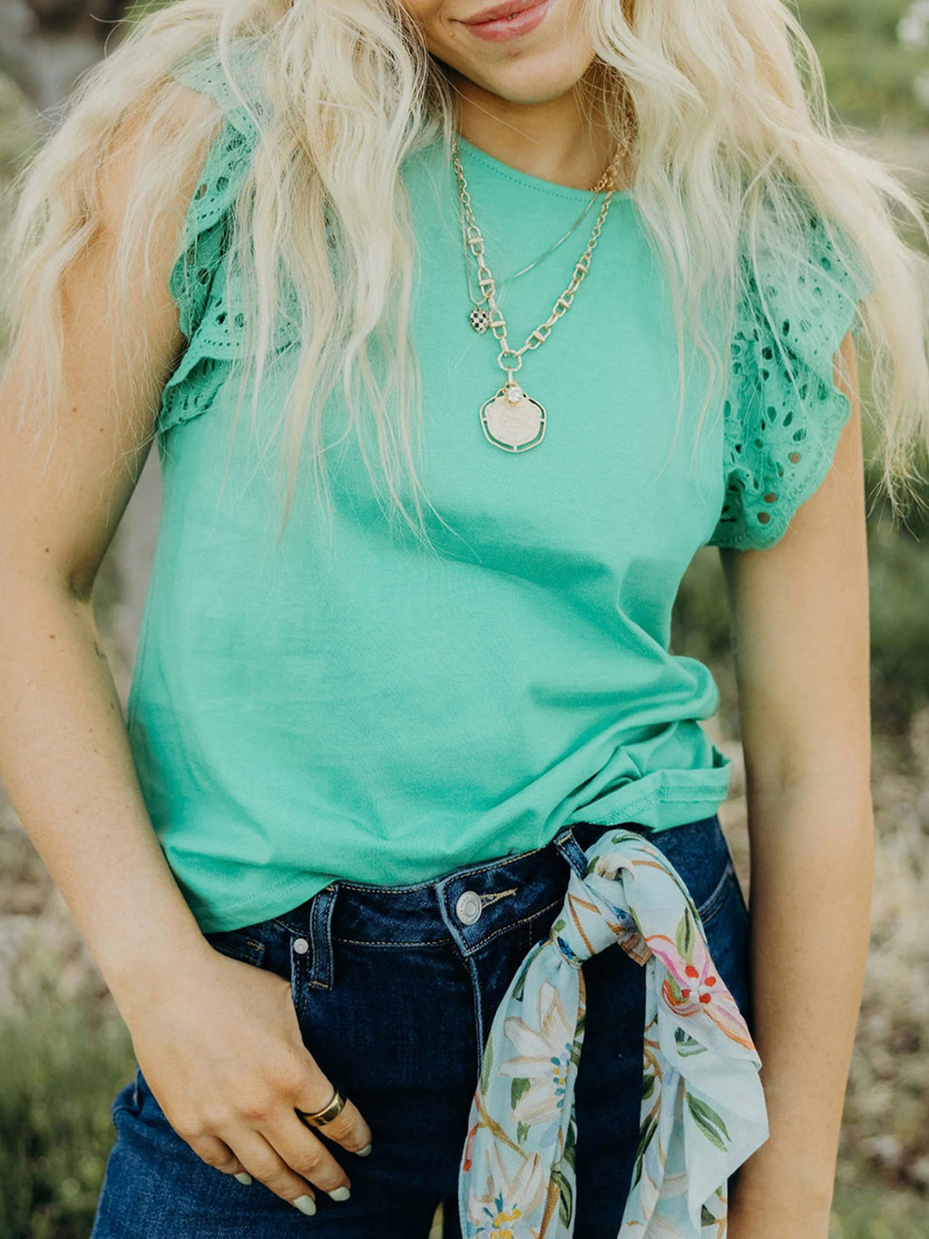 Ruffled eyelet lace cap sleeve top with cutout detail, trendy women's blouse by Trendsi, featuring feminine lace and ruffle accents.