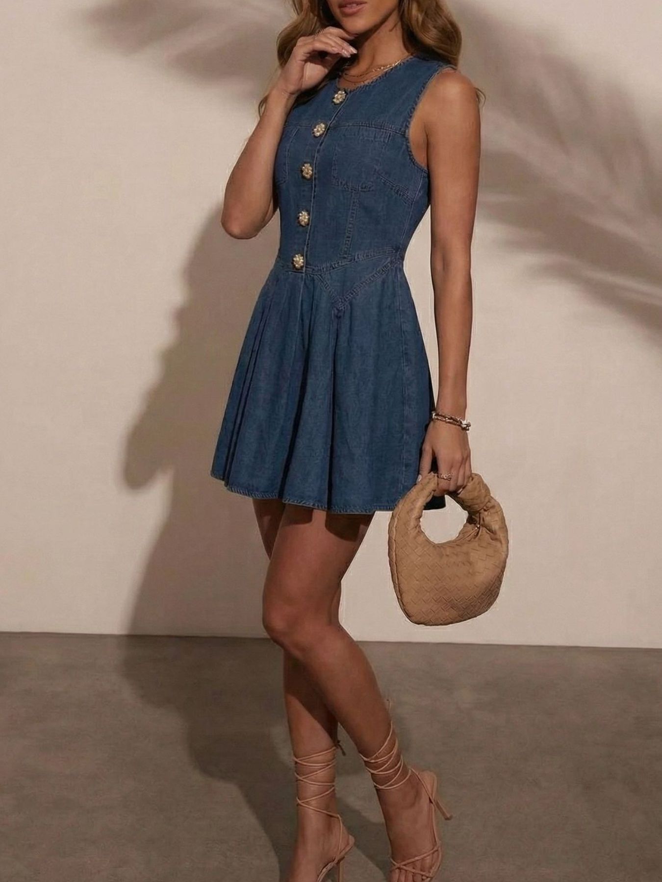 Women's sleeveless denim mini dress by Trendsi with button-front design and stretchy cotton blend fabric, shown on a model.