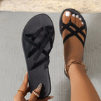 Black Plush Fashion Hub flat strappy cross-strap beach sandals with minimalist design and comfortable flat sole.