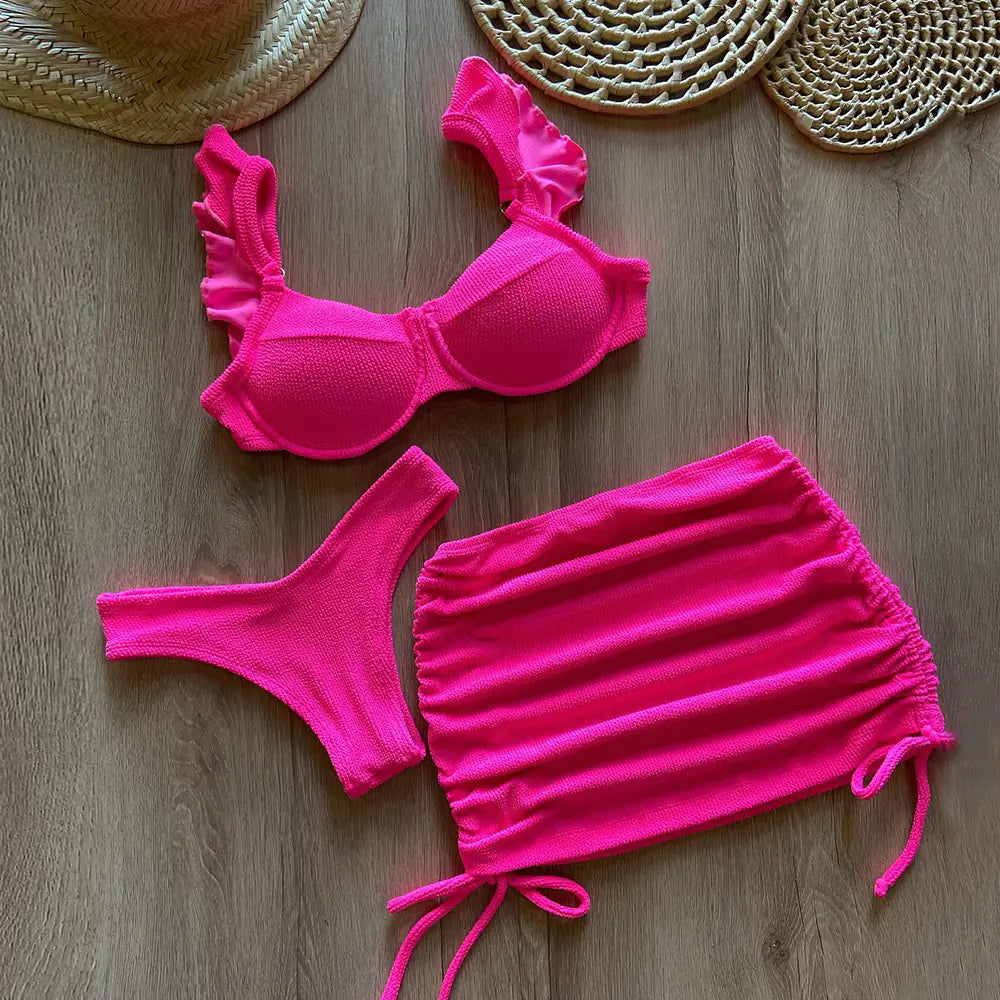 Women's solid color three-piece bikini set featuring a bikini top, bottoms, and cover-up in vibrant fabric, perfect for beachwear.