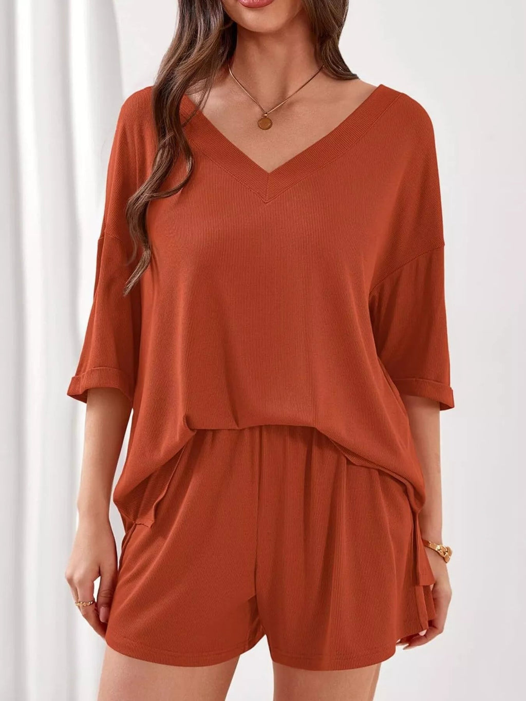 Women's casual V-neck top and shorts set in solid color, trendy two-piece outfit by Trendsi. Perfect for relaxed, stylish wear.