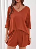 Women's casual V-neck top and shorts set in solid color, trendy two-piece outfit by Trendsi. Perfect for relaxed, stylish wear.