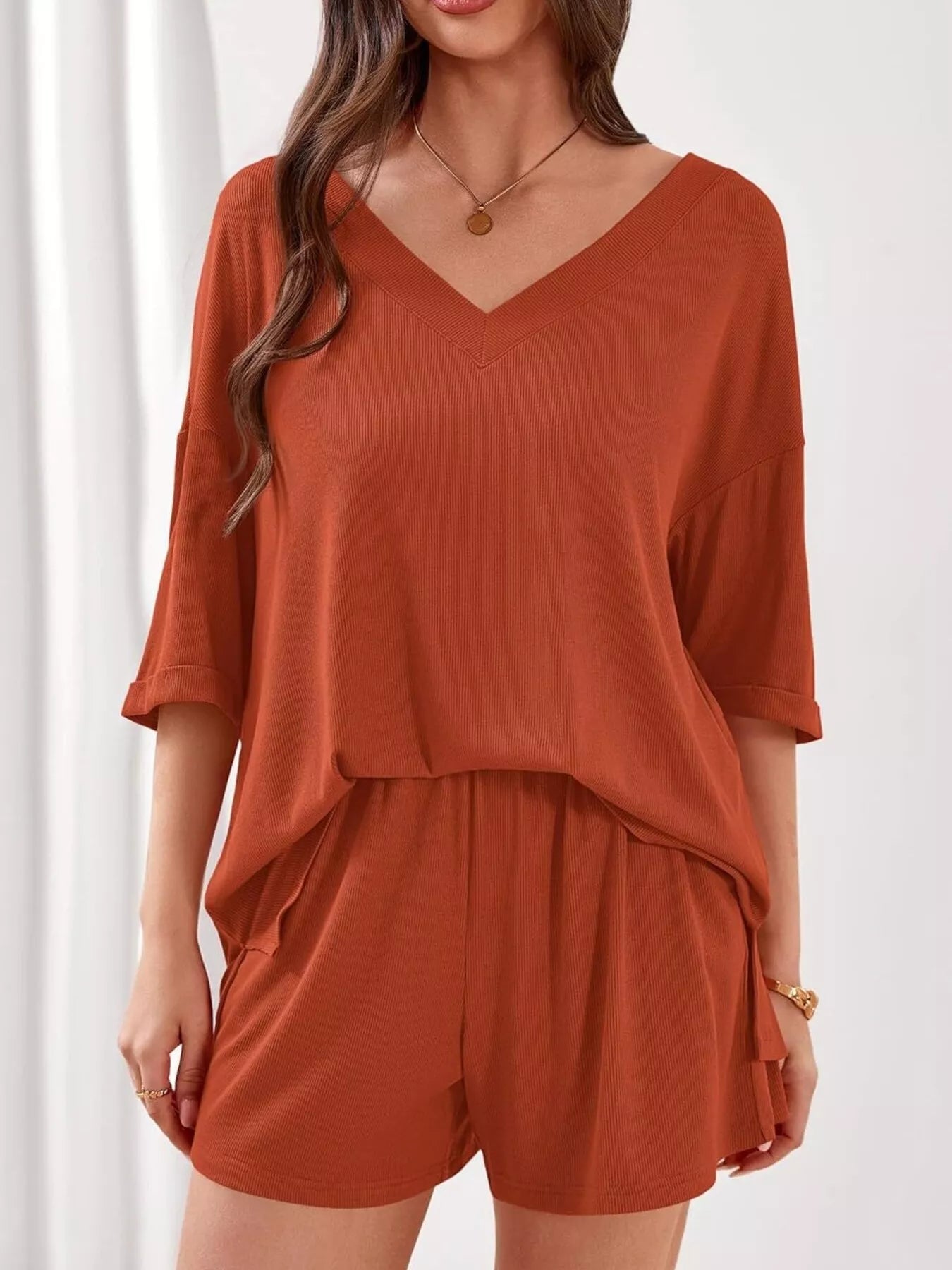 Women's casual V-neck top and shorts set in solid color, trendy two-piece outfit by Trendsi. Perfect for relaxed, stylish wear.