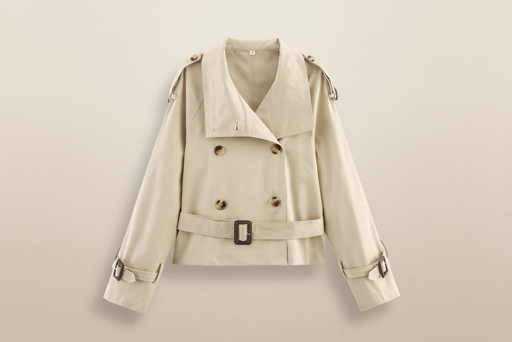 Women's short trench coat with notch collar and belt buckle detail, stylish jacket by Plush Fashion Hub.
