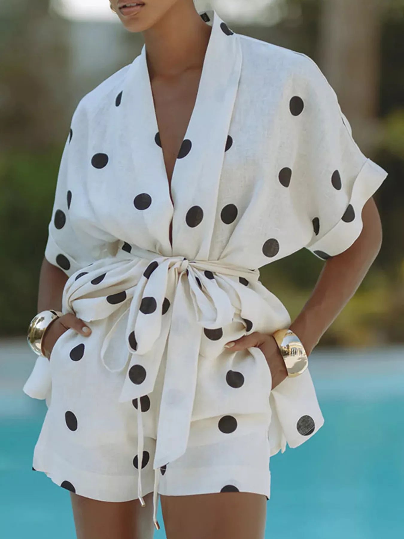 Women's polka dot tie waist top and shorts set by Trendsi, casual two-piece outfit with a relaxed fit and stylish design.